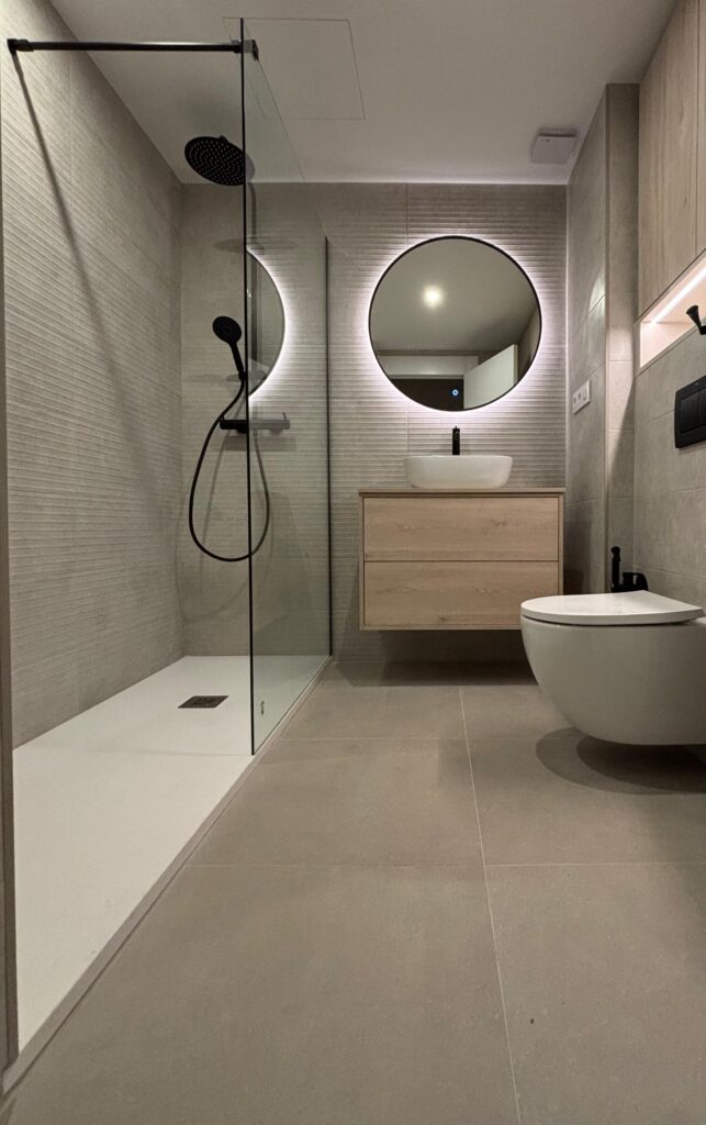 Baño con mampara de perfilería negra y pared de ducha texturizada