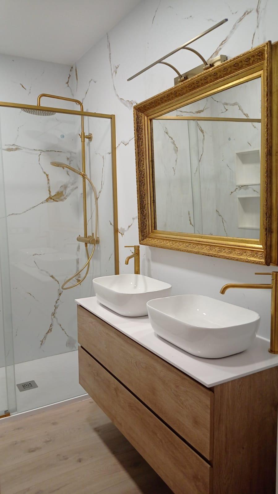 Grifería empotrada dorada sobre revestimiento de mármol blanco