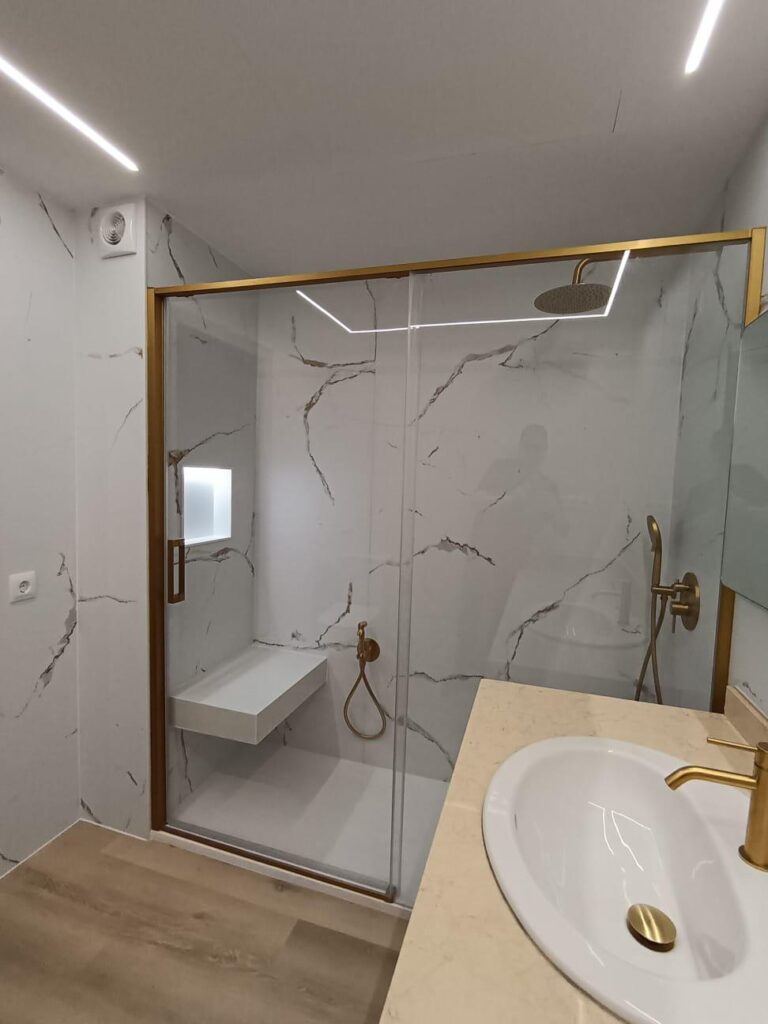 Ducha de obra a ras de suelo con banco integrado y mampara transparente