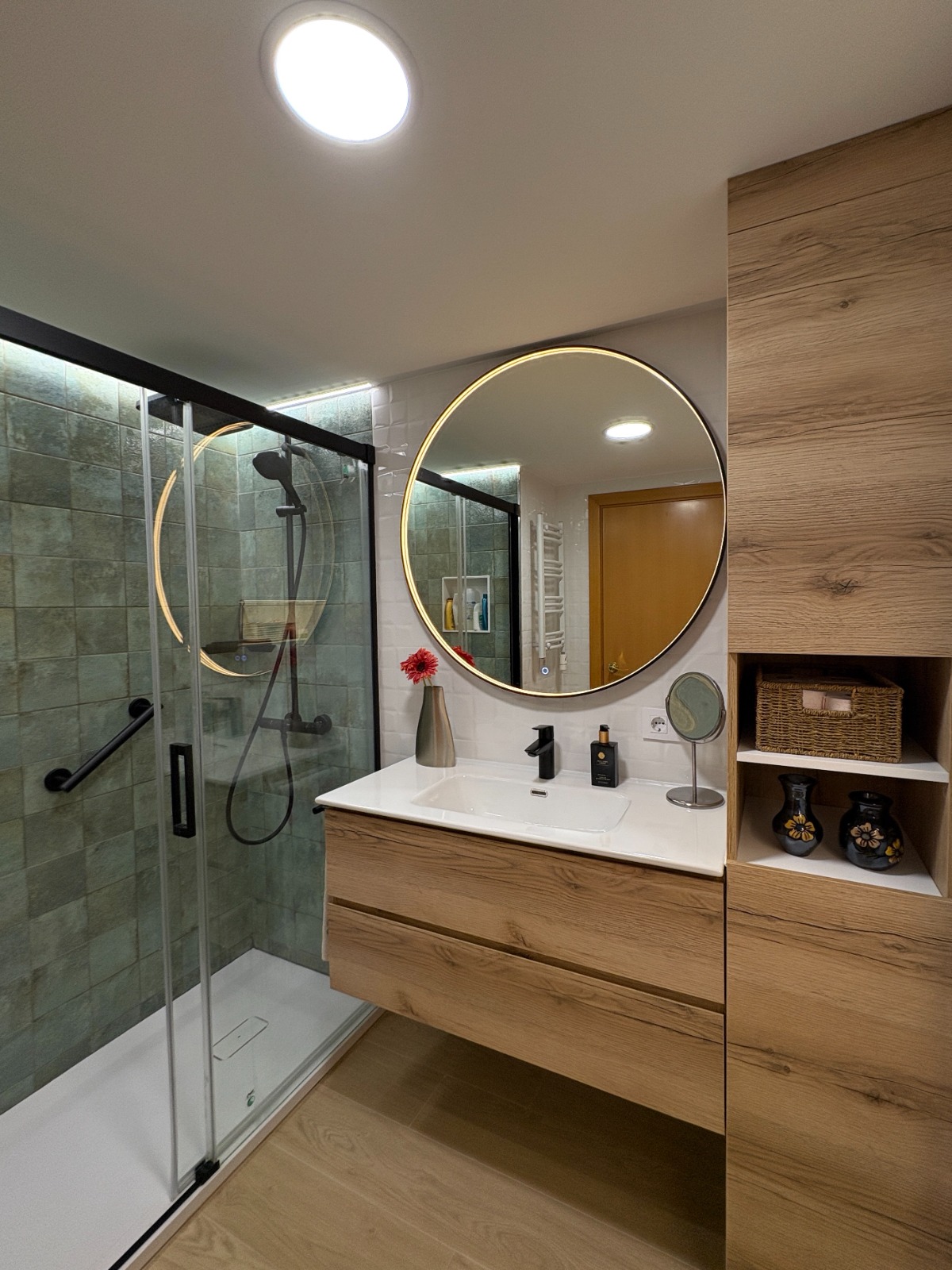 Baño moderno con espejo circular LED y mueble de madera roble